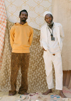 Two men posing in front of textiles